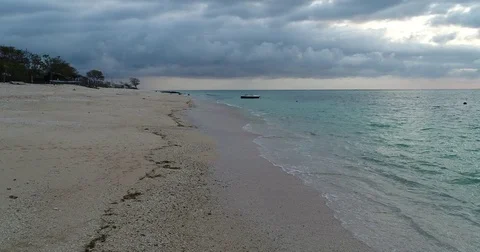4K static view of trpoical waves lapping on coral beach with fishing boat and  Stock Footage 81687081