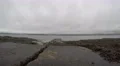 4K stone pier going out in the sea with seaweed all around it, grey clouded sky 4k or 4k+ Resolution