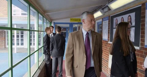 4K Strict teacher in inner city school disciplining pupil for scruffy uniform Stock Footage 76956017