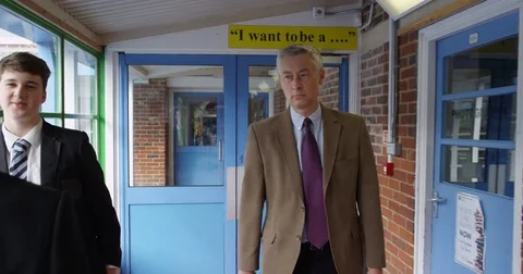 4K Strict teacher walking through school, reprimanding student for messy uniform Stock Footage 77283920
