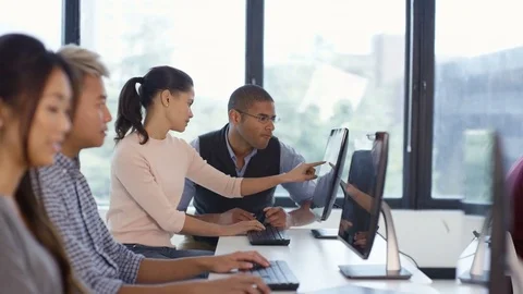 4K Students working on computers &amp; teacher giving help in adult education class. Stock Footage 73172296