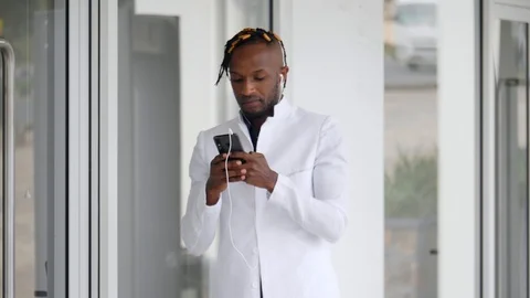 4k Stylish young boy in white jacket walking around the coffee shop using phone. Видео 111325645