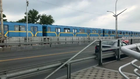 4K. Subway passing over the bridge near the city road. Cars drive along the Stock Footage 133709801