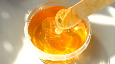 4K. Sugar paste or wax honey in a transparent jar on a white background. Video stock 153782935