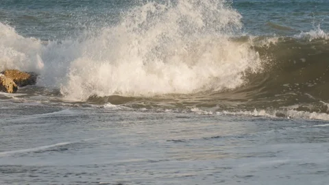 4k sunrise or sunset  static shot of waves crashing on rocks by a sandy beach. Stock Footage 123469833