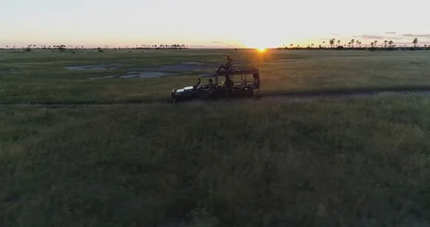 4K sunset aerial side view of a safari vehicle and tourists driving through the Stock Footage 95192926