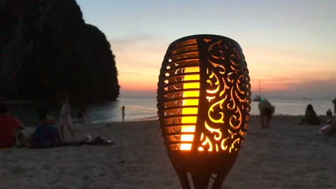 4K sunset on the beach. Close-up flame of a torch candle Stock Footage 136987077