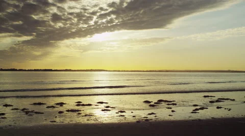 4K - Sunset on a beach as waves gently come to shore Stock Footage 50144200