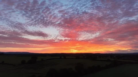 4K Sunset Glow Beneath Dramatic Cloudy Sky Over Rural Landscape Vídeo Stock 338307132