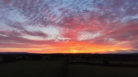 4K Sunset Glow Beneath Dramatic Cloudy Sky Over Rural Landscape Stock Footage 338307133