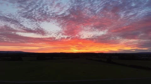 4K Sunset Glow Beneath Dramatic Cloudy Sky Over Rural Landscape 스톡 동영상 338307141
