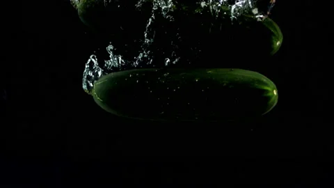 4K Super Slow-Mo Of Cucumbers Falling In Water Tank On Black Background Stock Footage 151534345