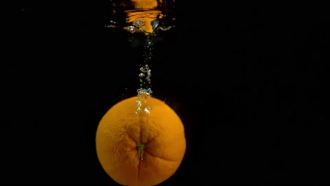 4K Super Slow-Mo Of Orange Bouncing In Water Tank On Black Background Stock Footage 151389389