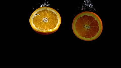 4K Super Slow-Mo Of Orange Slices Dive Into Water Tank On Black Background Stock Footage 151393447