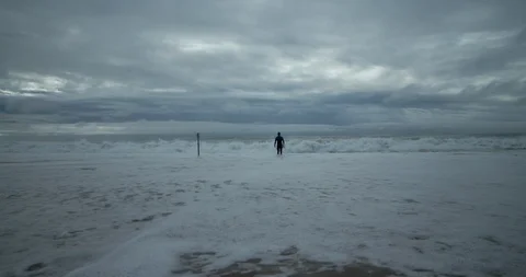 4K Surfer Standing In The Water As The Waves Wash On the Beach 库存影片 111662516
