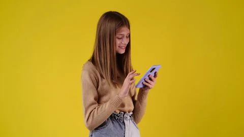 4k svideo of one girl using her phone over yellow background. Video stock 234013895