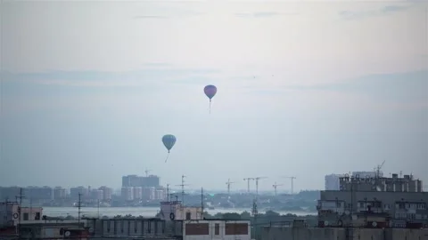 4K. Takeoff of two balloons over the city against the blue sky. Stock Footage 133646207