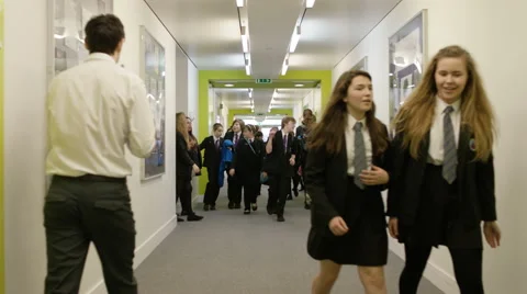 4K Teachers &amp; young students chatting &amp; walking through busy school corridor Video stock 60769596