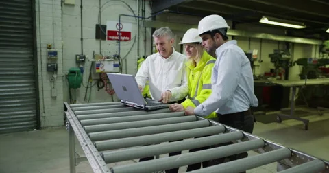4K Team of workers in warehouse or factory looking at laptop &amp; discussing work Stock Footage 67138204