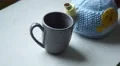 4K teapot with chick on teacosy pours cup of tea into grey cup 4k or 4k+ Resolution