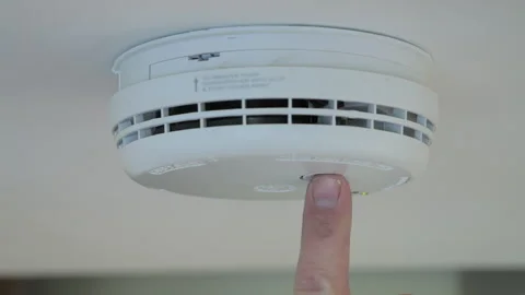 4K: Testing a smoke alarm in a house. A man uses his finger to push the button. Stock Footage 326778483