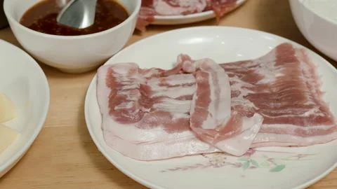 4K, Thinly sliced red pork is placed on a plate to prepare sukiyaki on a tabl Stock Footage 168230332