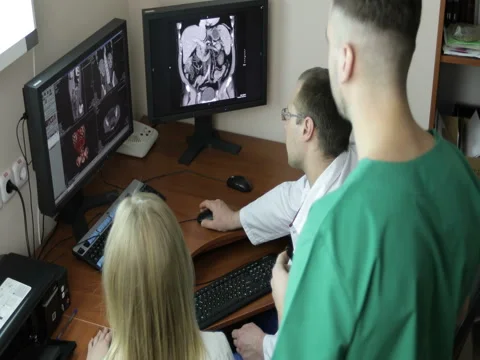 4K Three Doctors analyzing x-ray charts on the PC computer. Stock Footage 73670468