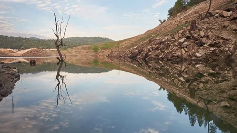 4k Time Lapse of Clouds Passing over A Lake and a Dead Tree Stock Footage 69777936