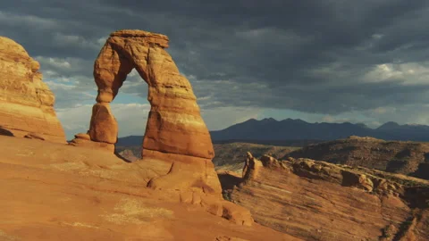 4K time lapse of dark summer clouds in blue sky casting shadows on Delicate Arch Stock Footage 138115400