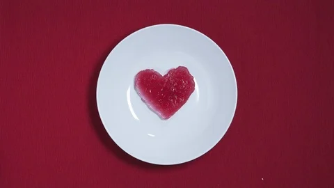 4K Time lapse heart from ice melting to water on red background. Top view Vidéo 121556637