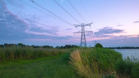4K Time-lapse, High-voltage lines tower cross over grass land at sunset Video stock 244845467