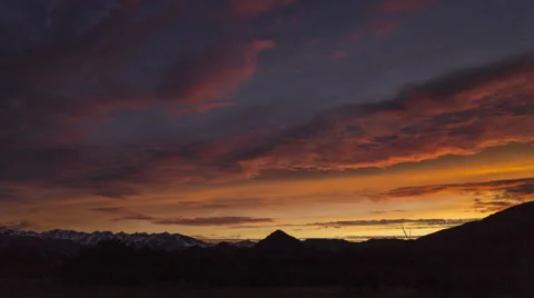 4K time lapse of an orange sky above snow-capped mountains during sunrise Stock Footage