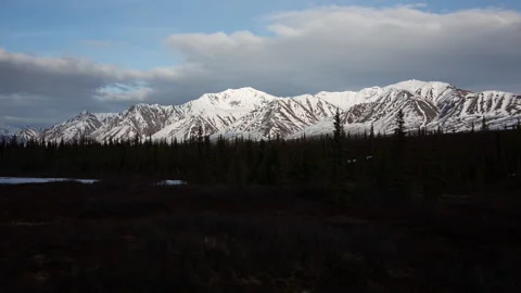 4K time lapse of sunset cloud shadows on snowy mountains and pines in Alaska Stock Footage 242722986