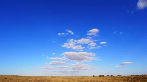 4K. Time lapse. White clouds in the blue sky over the yellow steppe. Stock Footage 96265348