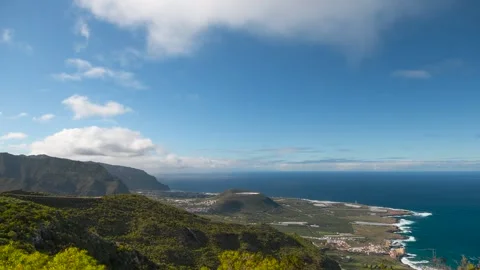 4K time-lapse of white clouds drifting over green hills and coastal landscape, T Stock Footage 329671360