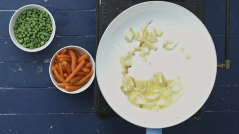 4k Time lapse of woman's hands preparing and frying onions, peas and carrots in Stock Footage 199615969