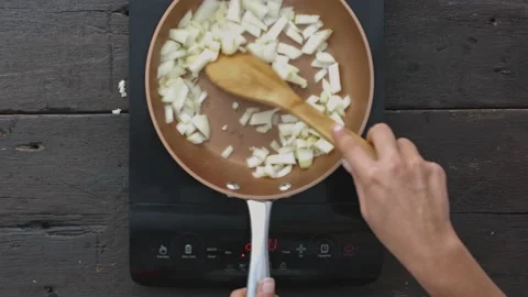 4k time lapse of woman's hands preparing fried onions on digital induction stove Stock Footage 199615993