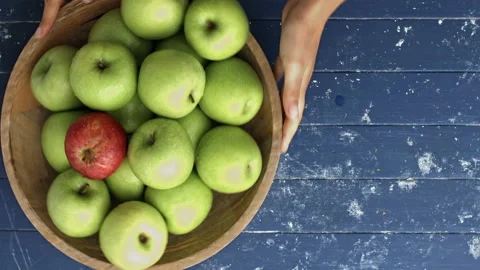 4k Time lapse of woman's hands eating red apple out of a wooden bowl full of gre Stock Footage 199616571