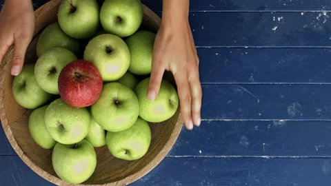 4k Time lapse of woman's hands choosing and turning wooden bowl full of green ap Stock Footage 199616593