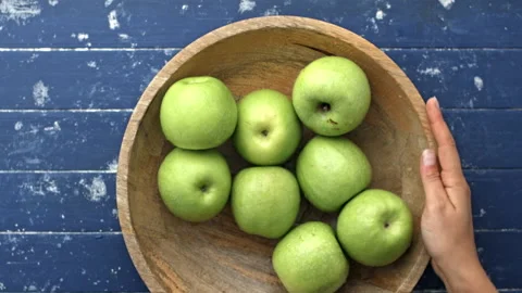 4k Time lapse of woman's hands choosing green apples out of wooden bowl until em 動画素材 199616601