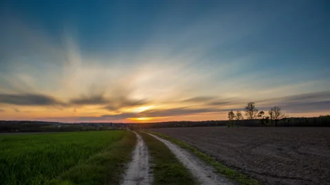 4k timelapse with beautiful, dramatic sunset sky over spring field and road Stock Footage 154404229