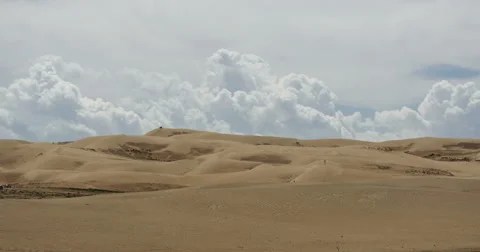 4k timelapse large white puffy cloud mass rolling over desert sand dunes. Stock Footage 43539456