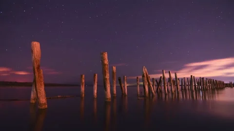 4k Timelapse of Night at the sea - Moving stars and clouds above columns. Stock Footage 220087587