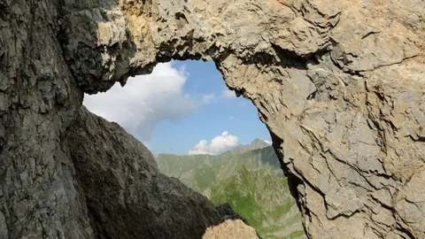 4k timelapse shot looking through a stone arch in Fagaras Mountains, Romania,. Stock Footage 77483631