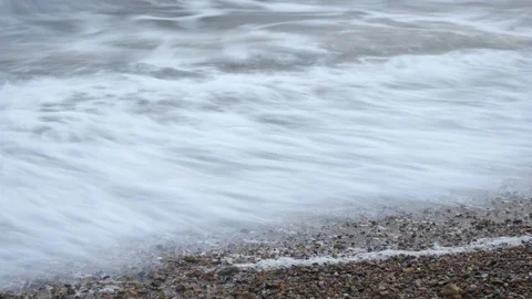4K timelapse of waves on pebble beach cloudy day Stockbeeldmateriaal 95810591