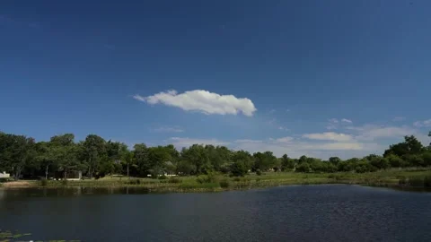 A 4k Timelapse of wind blowing on a pond lake with people on canoes moving Stock Footage 258019233
