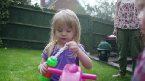 4K Toddler twins playing in the garden with older sister & their mother Stock Footage