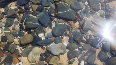 4K top-down shot of smooth ocean pebbles submerged under shallow water 動画素材 346168489