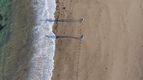 4K top-down view of couple walking along sandy beach washed by Atlantic Ocean wa Video stock 310804558