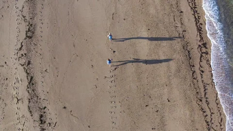 4K top-down view of couple walking along sandy beach washed by Atlantic Ocean wa Video stock 319927572